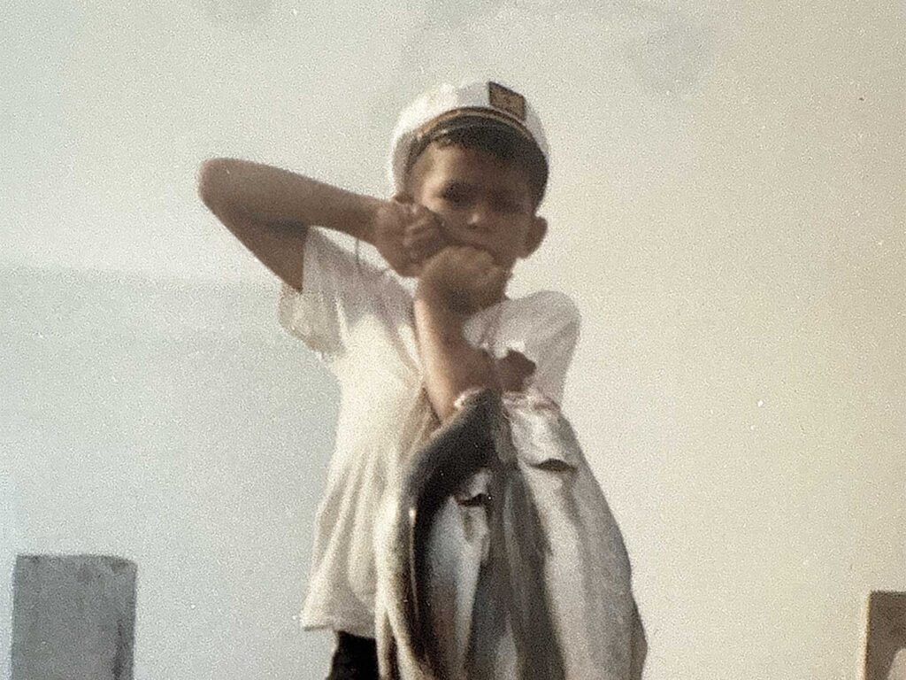 A vintage photo of young Rom Whitaker holding up a string of freshly caught fish.