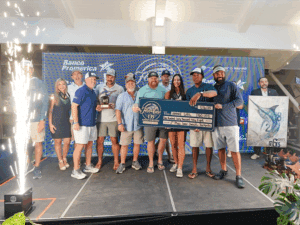 A team of sport-fishing anglers on stage at the 2025 Flor de Cana tournament at Marina Pez Vela. They hold up prizes and awards.