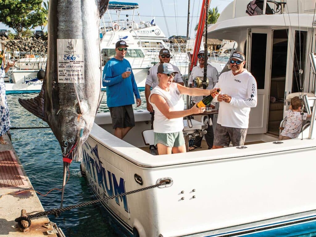 Anglers celebrating a large marlin weigh-in.