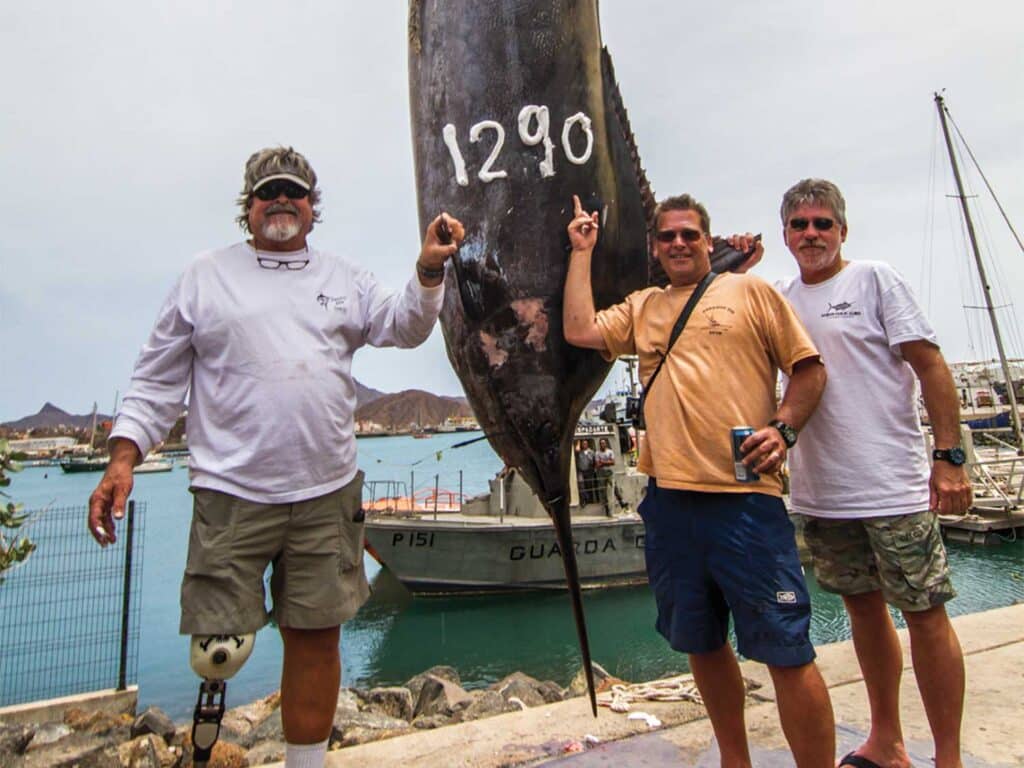 A team of anglers and Randy Hodgekiss stand next to a large 1,290 pound marlin.