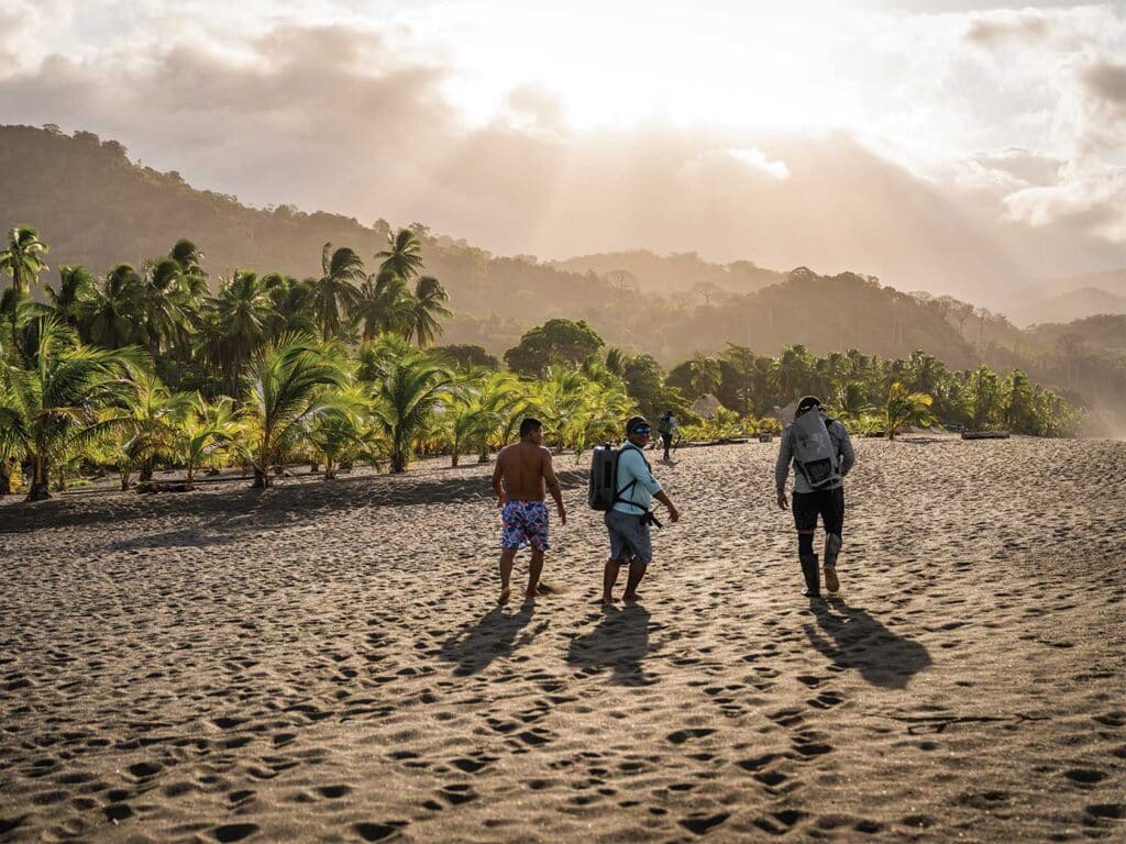 Three people walking on a beach in Panama.