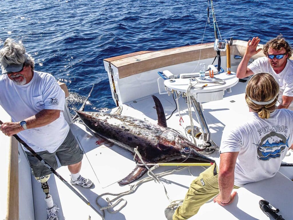 Capt Randy Hodgekiss next to a large marlin pulled into the cockpit.