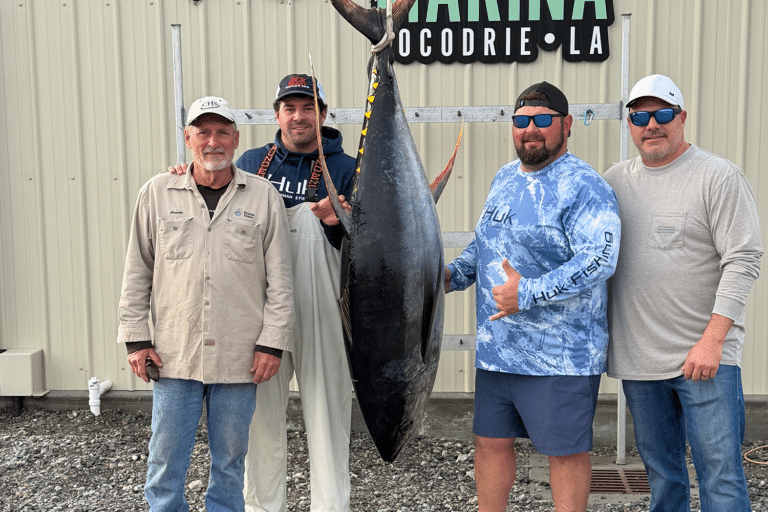 Anglers standing beside tuna.