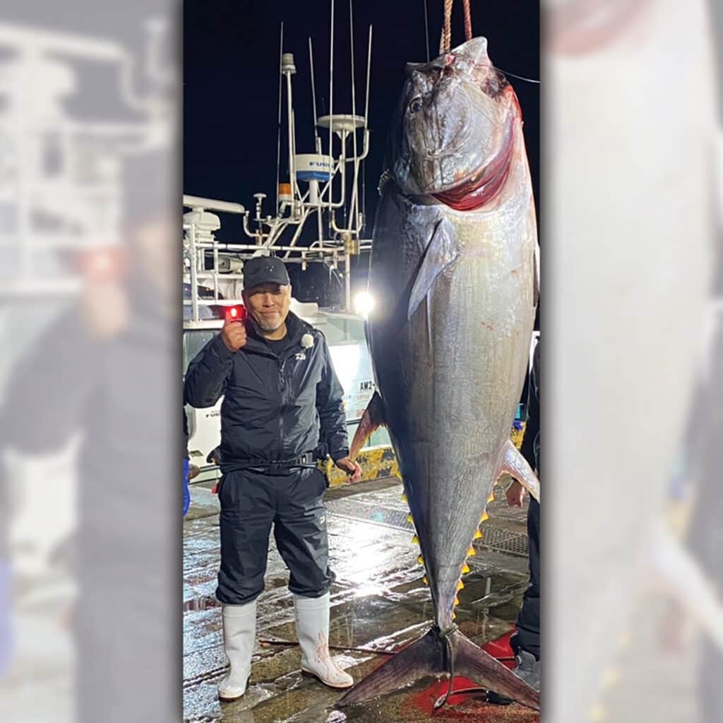 A boat captain next to a large tuna.