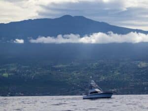 A sport-fishing boat cruises past Hawaii's coastline.