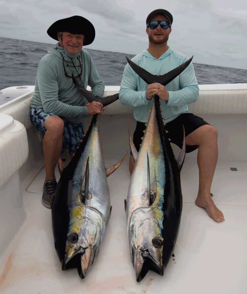 Two anglers holding tuna.